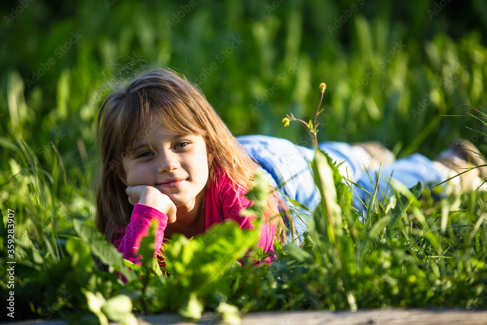 Cute pleasant little girl is lying in the green grass. Cute pleasant little girl is lying in the green grass.