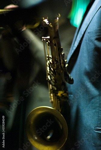 Canvas Print Jazz musician wearing suit holding saxophone in a dark neon night club