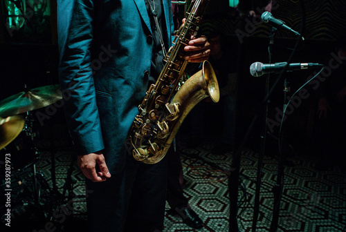 Photography Jazz musician wearing suit playing saxophone in a dark neon night club