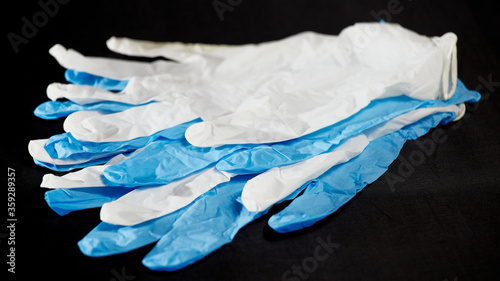 White and blue medical gloves on a black background