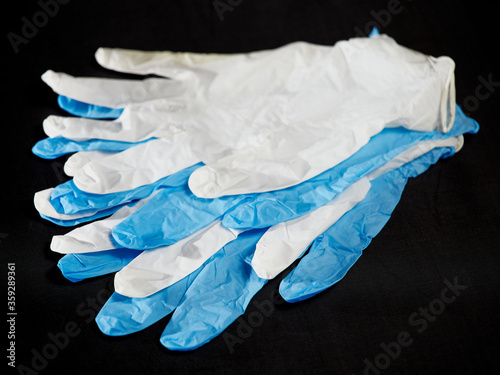 White and blue medical gloves on a black background