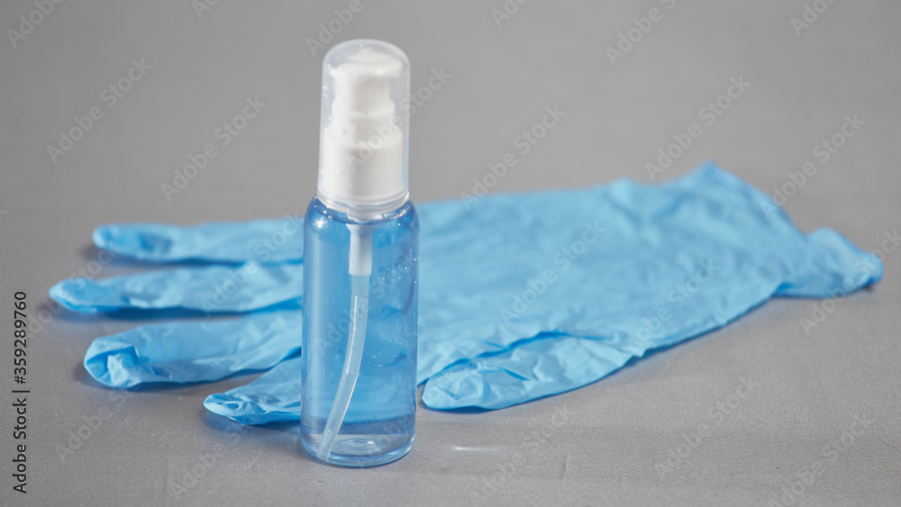 Tube with blue sanitizer and blue medical glove on a gray background Tube with blue sanitizer and blue medical glove on a gray background