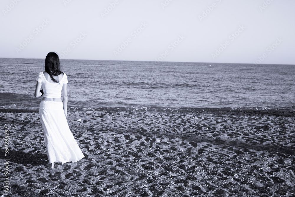 Girl dressed in white with her back to the beach Girl dressed in white with her back to the beach
