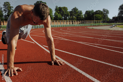 Shirtless muscular man doing push ups on the track at the stadium. Sportsman. Strong man