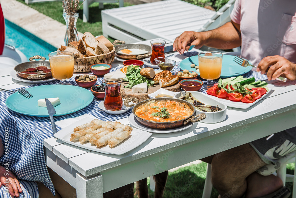 couple eating breakfast.Concept promotional morning breakfast in the hotel, tasty Egg Benedict,Turkish and French Breakfast, tea and orange juice. near swimming pool in the garden couple eating breakfast.Concept promotional morning breakfast in the hotel, tasty Egg Benedict,Turkish and French Breakfast, tea and orange juice. near swimming pool in the garden