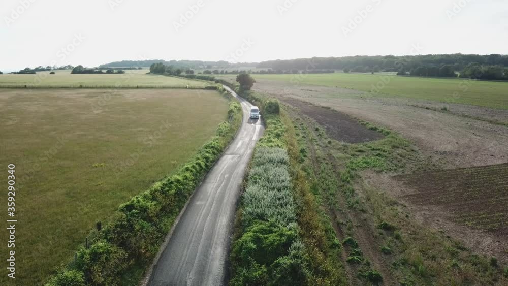Arial view from Drone following campervan on scenic road trough fields at sunset Arial view from Drone following campervan on scenic road trough fields at sunset