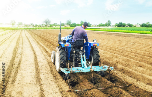 Farmer on a tractor making ridges and mounds rows on a farm field. Preparing the land for planting future crop plants. Cultivation of soil for planting. Agroindustry, agribusiness. European farmland. photo
