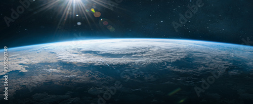 Ultra wide wallpaper of Earth in the outer space. Orbit of planet. Sun light and stars on background. Elements of this image furnished by NASA photo