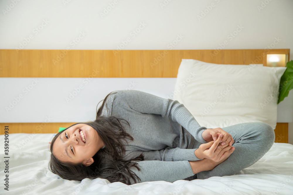 The girl is having fun sitting on the white bed and doing yoga exercises. The girl is having fun sitting on the white bed and doing yoga exercises.