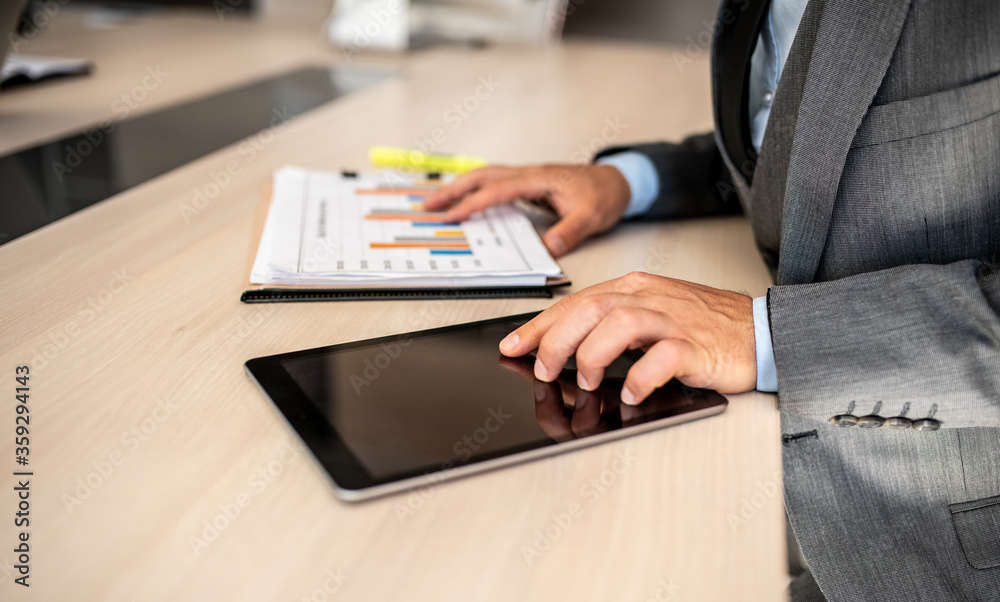 Closeup shot of a businessman analyzing statistics on a digital tablet in an office Closeup shot of a businessman analyzing statistics on a digital tablet in an office