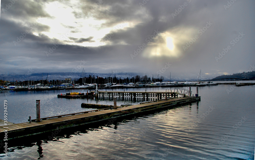 Dock on water with sunshine through clouds