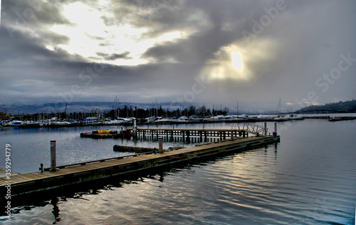 Dock on water with sunshine through clouds © Photos By Alisa