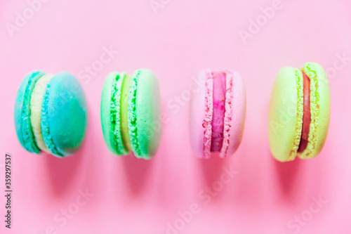 Sweet almond colorful pink blue yellow green macaron or macaroon dessert cake isolated on trendy pink pastel background. French sweet cookie. Minimal food bakery concept. Flat lay top view, copy space
