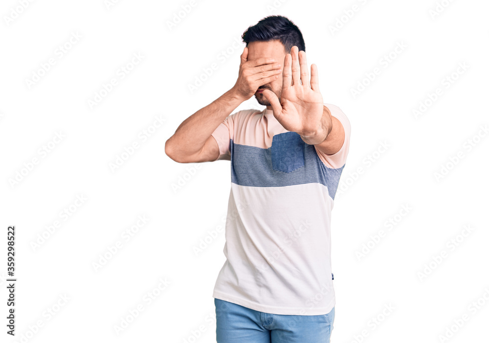 Young handsome man wearing casual clothes covering eyes with hands and doing stop gesture with sad and fear expression. embarrassed and negative concept. Young handsome man wearing casual clothes covering eyes with hands and doing stop gesture with sad and fear expression. embarrassed and negative concept.
