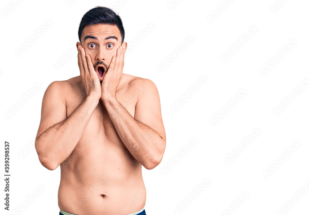 Fototapeta premium Young handsome man wearing swimwear afraid and shocked, surprise and amazed expression with hands on face
