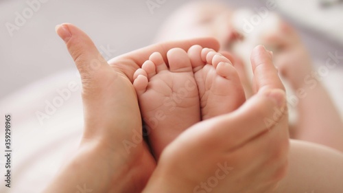 Mother massaging and tickling small baby feet. close up slow motion shot.