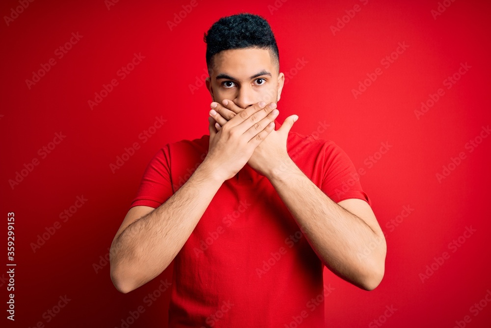 Young handsome man wearing red casual polo standing over isolated background shocked covering mouth with hands for mistake. Secret concept. Young handsome man wearing red casual polo standing over isolated background shocked covering mouth with hands for mistake. Secret concept.