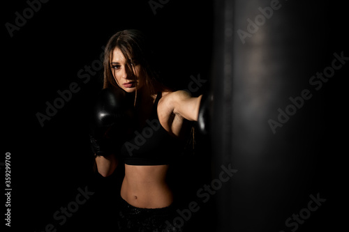 Female boxer training in the dark ring. Silhouette. Boxing concept. Fighter woman. Sexy girl with perfect body in gloves practicing her punches at a boxing studio. concept of health and sport. © MONIUK ANDRII