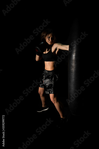 Female boxer training in the dark ring. Silhouette. Boxing concept. Fighter woman. Sexy girl with perfect body in gloves practicing her punches at a boxing studio. concept of health and sport.
