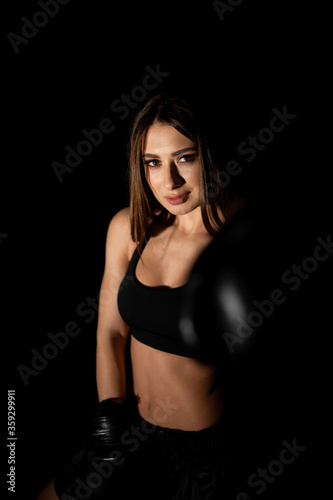 Female boxer training in the dark ring. Silhouette. Boxing concept. Fighter woman fist close up. Sexy girl with perfect body in boxing gloves at gym. concept of health and sport.