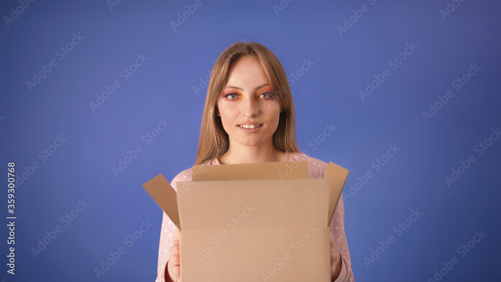 Young caucasian woman with packed cardboard boxes and surprised face isolated on the blue background. Copy space. Young caucasian woman with packed cardboard boxes and surprised face isolated on the blue background. Copy space.