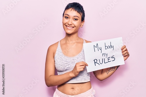 Fototapeta Young woman holding my body my rules banner looking positive and happy standing