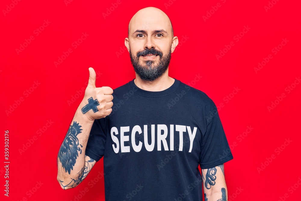 Naklejka premium Young handsome man wearing security t shirt smiling happy and positive, thumb up doing excellent and approval sign