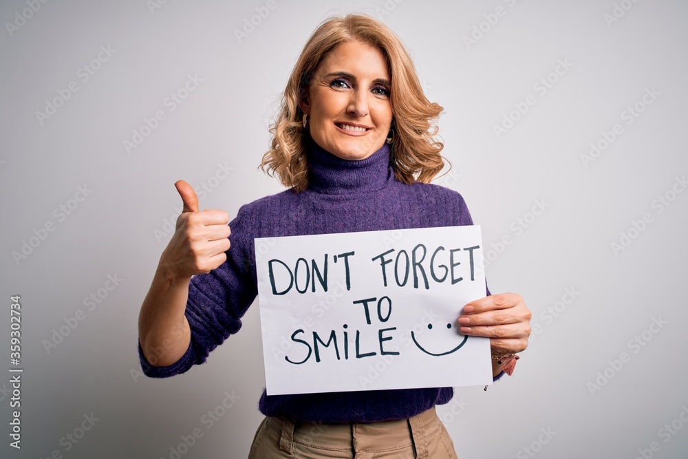 Middle age beautiful blonde woman holding banner funny positive message happy with big smile doing ok sign, thumb up with fingers, excellent sign Middle age beautiful blonde woman holding banner funny positive message happy with big smile doing ok sign, thumb up with fingers, excellent sign