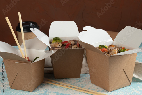 Eco packaging - noodles with vegetables, chicken and meat in craft packaging for the delivery service. Fast food.