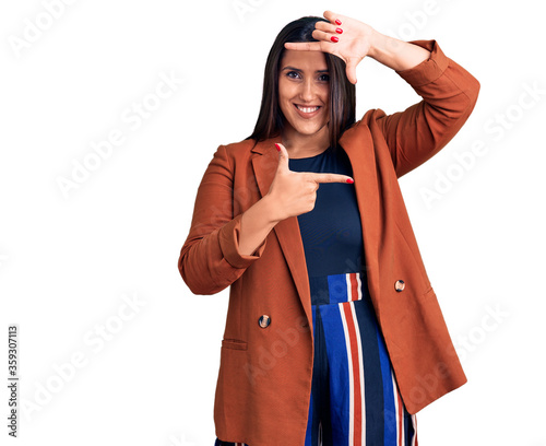 Young beautiful brunette woman wearing elegant clothes smiling making frame with hands and fingers with happy face. creativity and photography concept. © Krakenimages.com