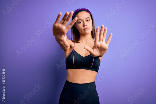 Young beautiful sporty girl doing sport wearing sportswear over isolated purple background doing frame using hands palms and fingers, camera perspective © Krakenimages.com