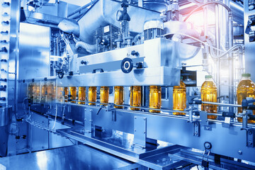 Beverage factory, Conveyor belt with juice in bottles, Industrial Interior in blue color, food and drink production line process.
