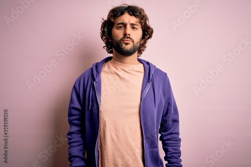 Young handsome sporty man with beard wearing casual sweatshirt over pink background looking at the camera blowing a kiss on air being lovely and sexy. Love expression. © Krakenimages.com
