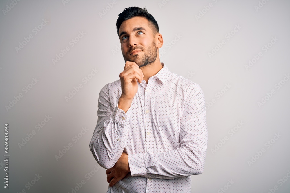 Young handsome man wearing elegant shirt standing over isolated white background with hand on chin thinking about question, pensive expression. Smiling and thoughtful face. Doubt concept. Young handsome man wearing elegant shirt standing over isolated white background with hand on chin thinking about question, pensive expression. Smiling and thoughtful face. Doubt concept.