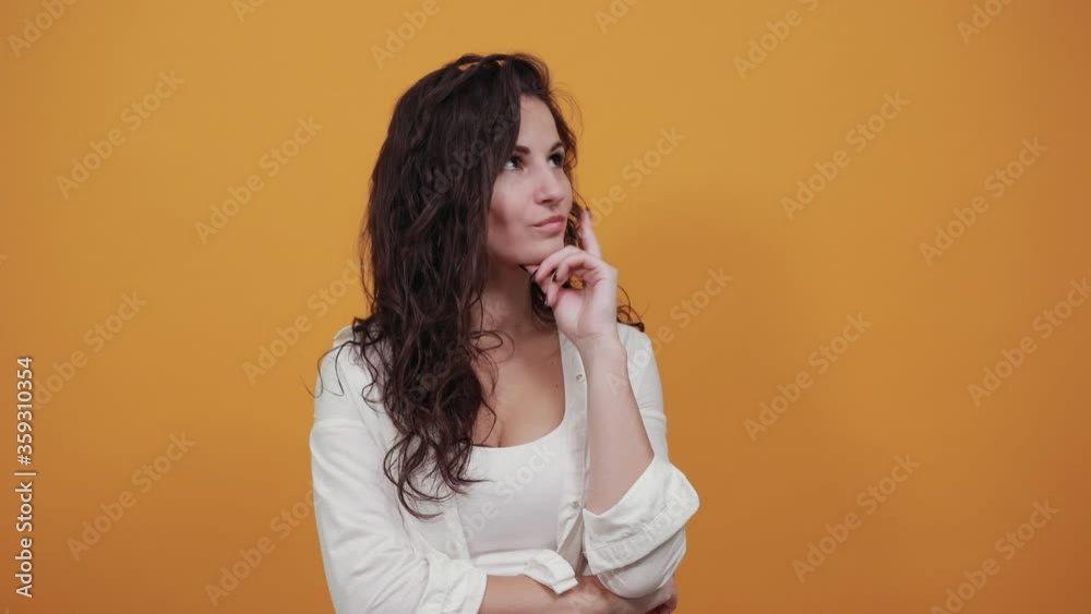 Hand on chin thinking about question, pensive expression. Doubt. Thoughtful face. Using that incredibly sharp business mind. Young attractive woman, dressed white blouse, with brown eyes, curly hair Hand on chin thinking about question, pensive expression. Doubt. Thoughtful face. Using that incredibly sharp business mind. Young attractive woman, dressed white blouse, with brown eyes, curly hair