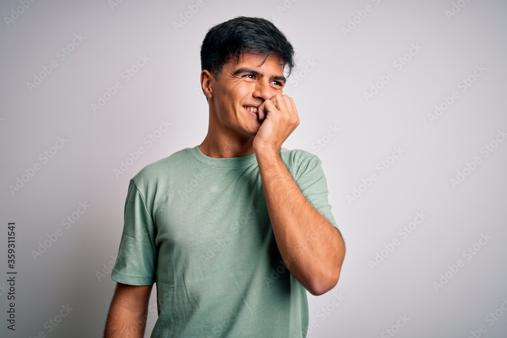 Young handsome man wearing casual t-shirt standing over isolated white background looking stressed and nervous with hands on mouth biting nails. Anxiety problem. Young handsome man wearing casual t-shirt standing over isolated white background looking stressed and nervous with hands on mouth biting nails. Anxiety problem.