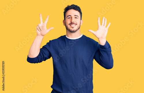 Young hispanic man wearing casual clothes showing and pointing up with fingers number eight while smiling confident and happy.