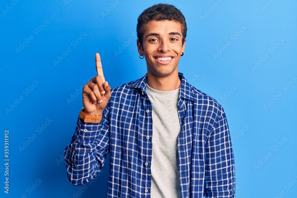 Young african amercian man wearing casual clothes smiling with an idea or question pointing finger up with happy face, number one Young african amercian man wearing casual clothes smiling with an idea or question pointing finger up with happy face, number one
