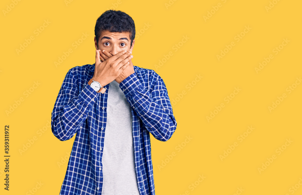 Young african amercian man wearing casual clothes shocked covering mouth with hands for mistake. secret concept. Young african amercian man wearing casual clothes shocked covering mouth with hands for mistake. secret concept.