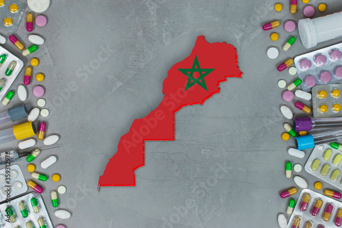 The Morocco State began research for treatment and medicine to combat the pandemic outbreak disease coronavirus. Medicine, pills, needles, syringes and Morocco map and flag on gray background.