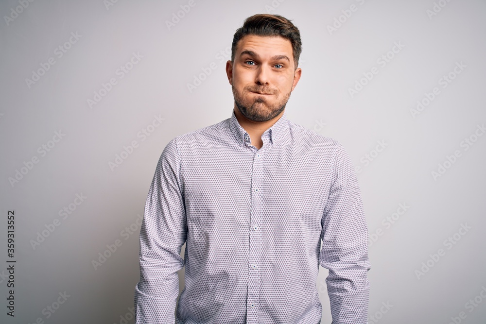 Young business man with blue eyes standing over isolated background puffing cheeks with funny face. Mouth inflated with air, crazy expression. Young business man with blue eyes standing over isolated background puffing cheeks with funny face. Mouth inflated with air, crazy expression.