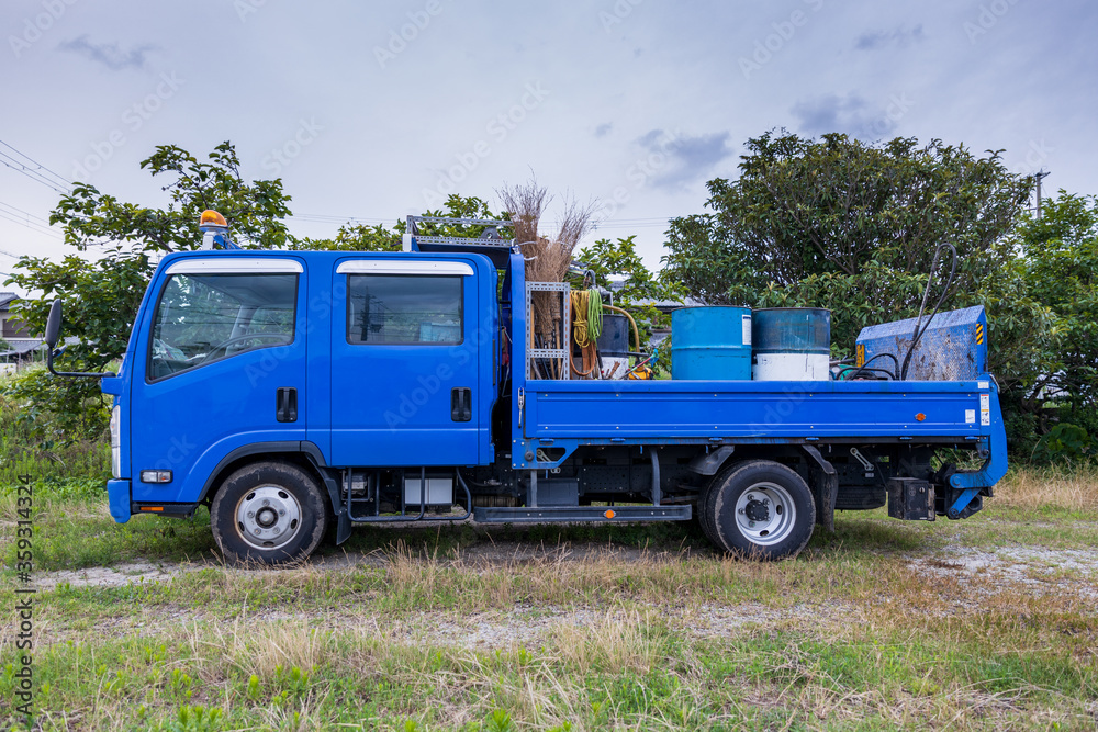 Side view of blue flatbed work truck with equipment in back