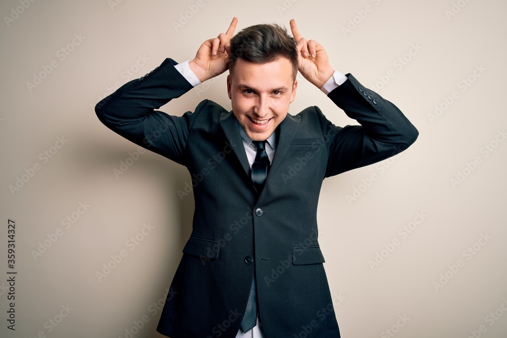 Young handsome business man wearing elegant suit and tie over isolated background Posing funny and crazy with fingers on head as bunny ears, smiling cheerful