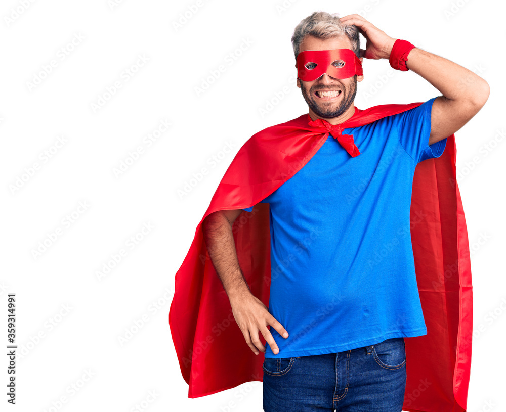 Young blond man wearing super hero custome confuse and wonder about question. uncertain with doubt, thinking with hand on head. pensive concept. Young blond man wearing super hero custome confuse and wonder about question. uncertain with doubt, thinking with hand on head. pensive concept.