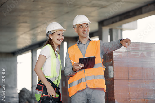 an engineer in the construction industry discusses a construction plan with a worker. Cheerful and smiling builders working together on the project