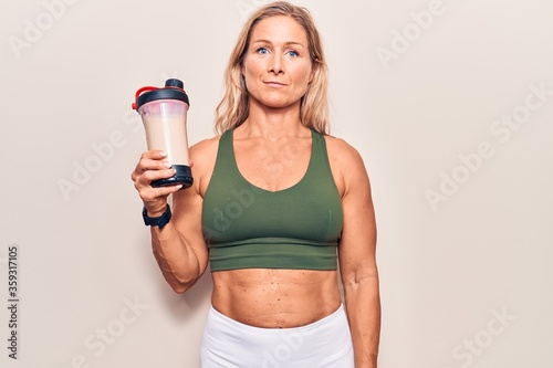 Middle age caucasian blonde woman wearing sport clothes drinking a protein shake thinking attitude and sober expression looking self confident © Krakenimages.com