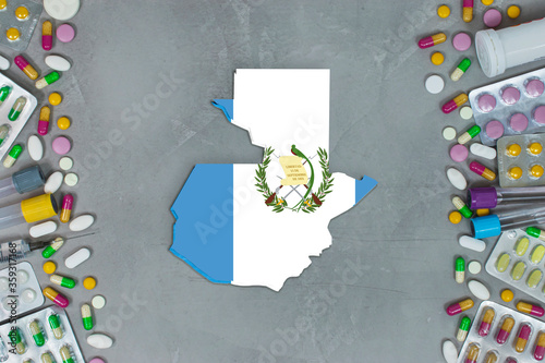 The Guatemala State began research for treatment and medicine to combat the pandemic outbreak disease coronavirus. Medicine, pills, needles, syringes and Guatemala map and flag on gray background.