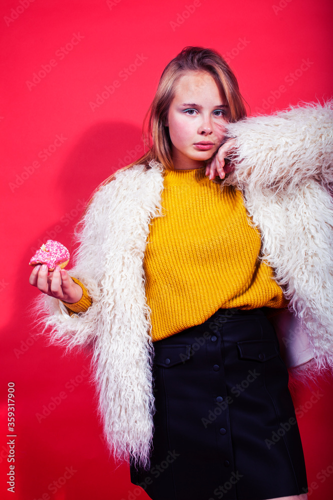 young pretty fashion teenage girl on bright red background holding donut, happy smiling lifestyle people concept young pretty fashion teenage girl on bright red background holding donut, happy smiling lifestyle people concept