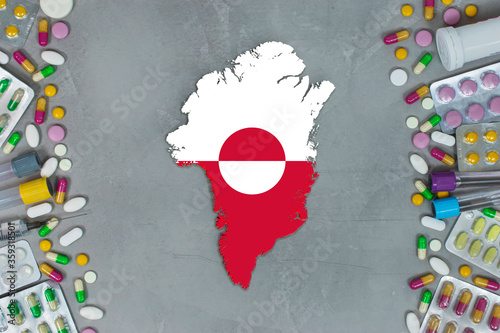 The Greenland State began research for treatment and medicine to combat the pandemic outbreak disease coronavirus. Medicine, pills, needles, syringes and Greenland map and flag on gray background.