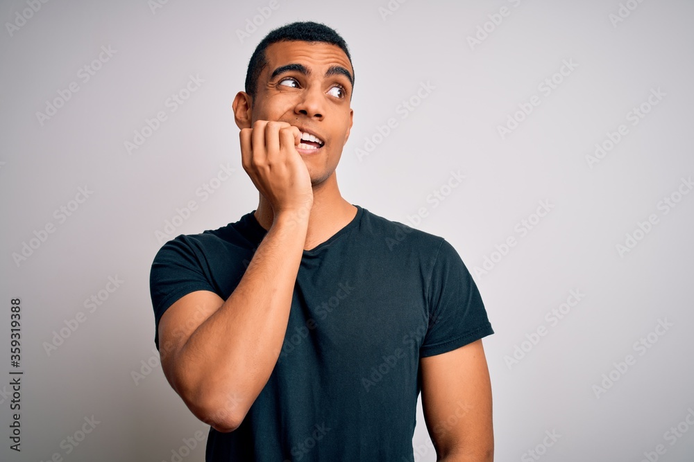 Young handsome african american man wearing casual t-shirt standing over white background looking stressed and nervous with hands on mouth biting nails. Anxiety problem. Young handsome african american man wearing casual t-shirt standing over white background looking stressed and nervous with hands on mouth biting nails. Anxiety problem.
